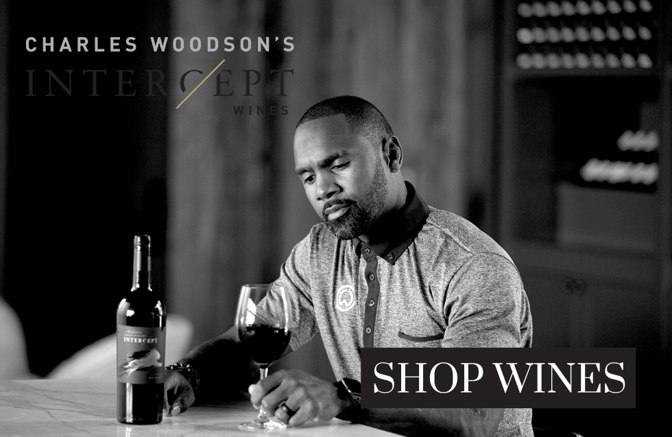 Charles Woodson's Intercept Wines. Charles Woodson at a table with a glass of wine.